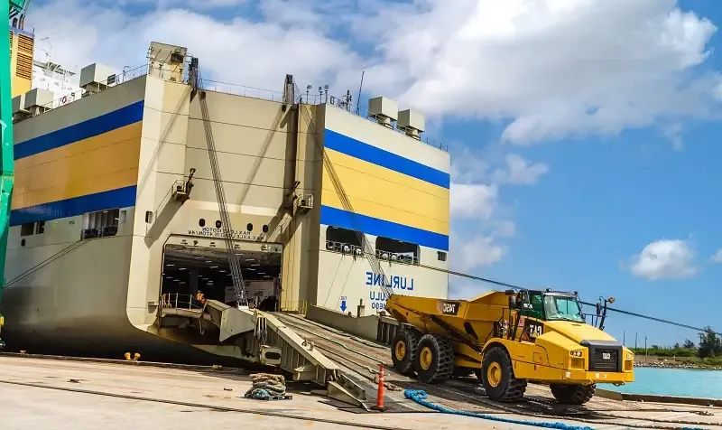 Yellow, oversized heavy equipment drives down the ramp of roll-on roll-off container ship Lurline.